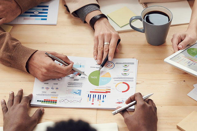 three people reviewing documents on a table with coffee